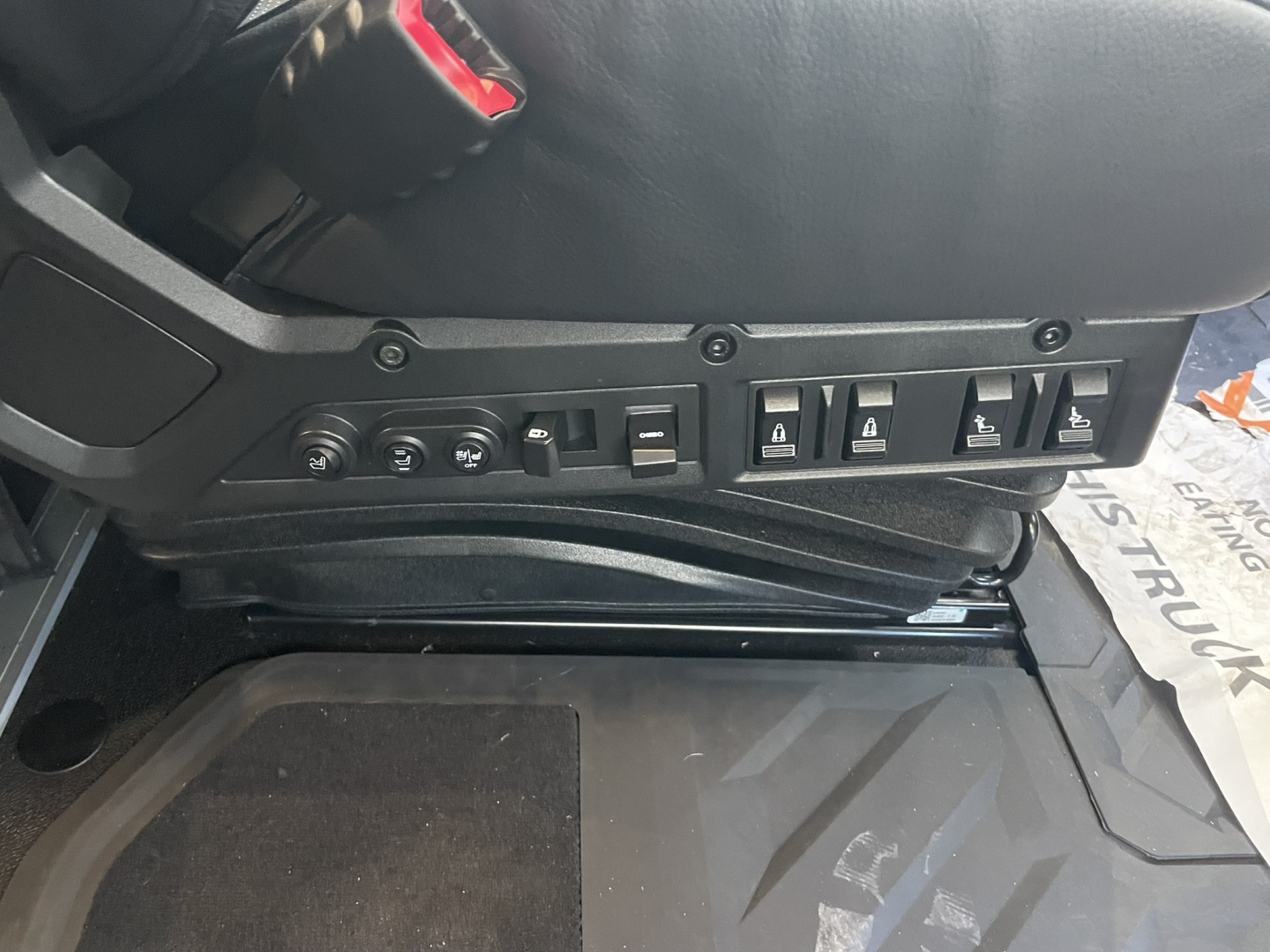 Interior view of a Mack PR64T76H cab dashboard/seat base with control switches and wiring, showing multiple rocker switches and a joystick-like control.