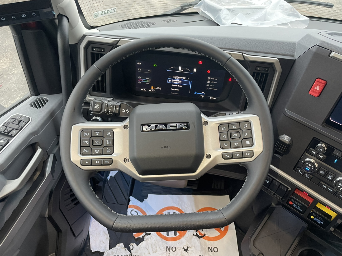 Mack PR64T76H truck steering wheel and dashboard view with digital display and control buttons on both sides.