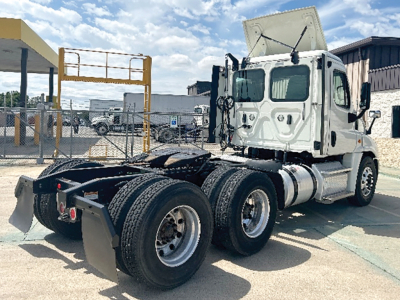 Truck chassis and cab of a 2018 Freightliner Cascadia125 daycab showing rear dual-axle configuration and raised hood with fuel tanks