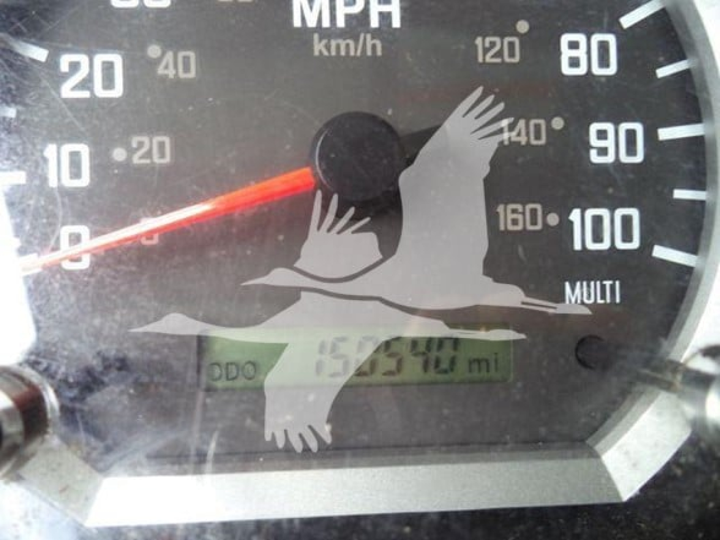 Dashboard gauge showing speedometer and odometer reading; green digital odometer display; partial Isuzu truck instrument cluster