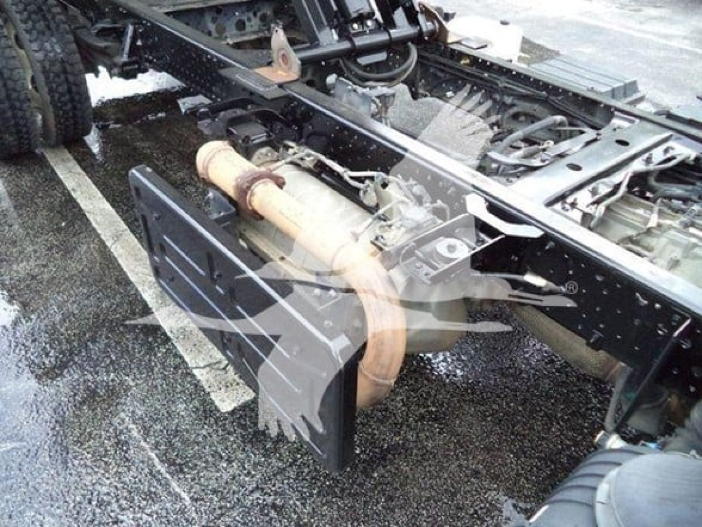 Truck chassis showing exhaust pipe and frame with fuel tank and underbody components visible.