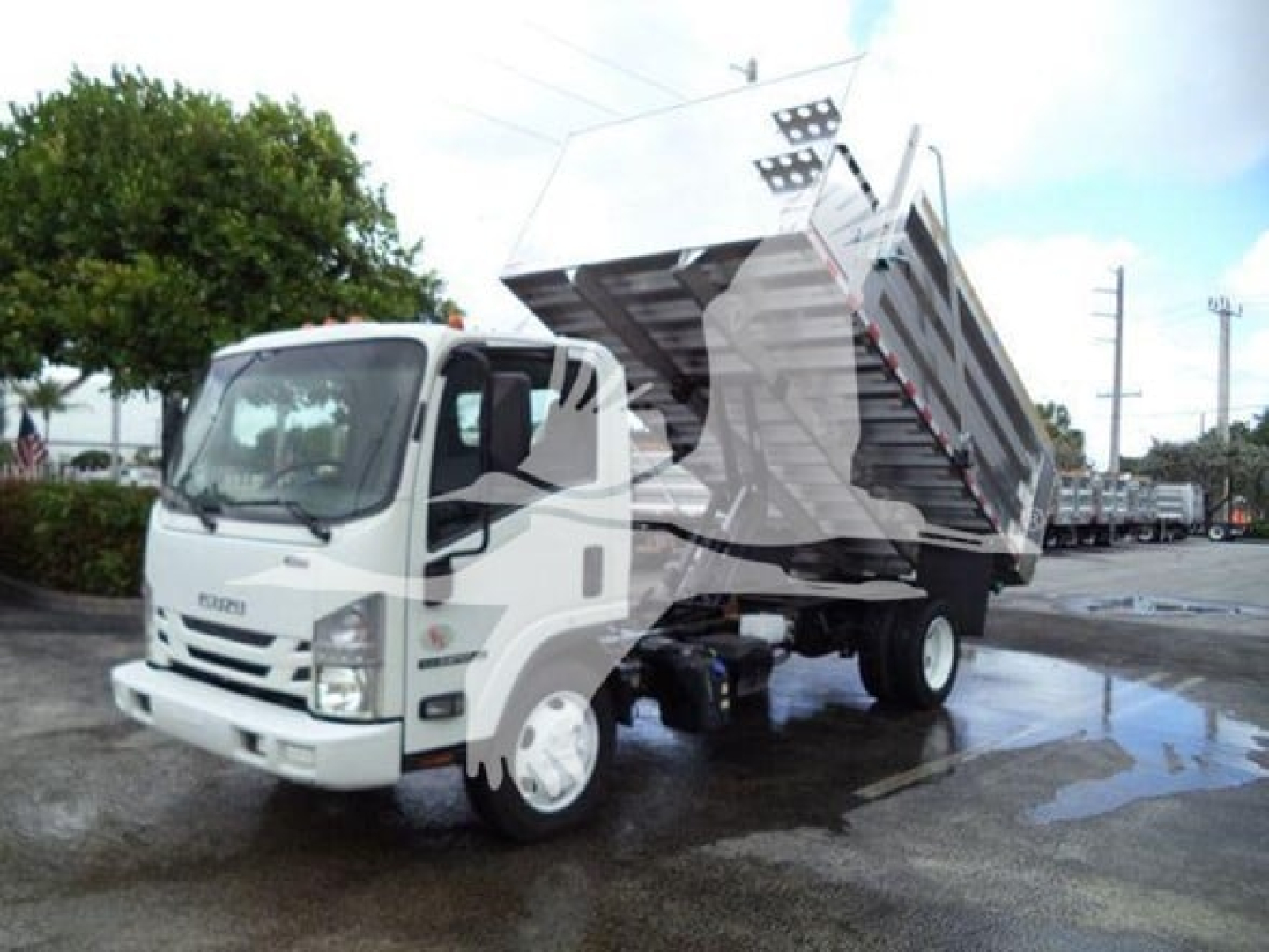 Isuzu NPR XD dump truck side view showing tipped cargo bed and hydraulic lift in operation.
