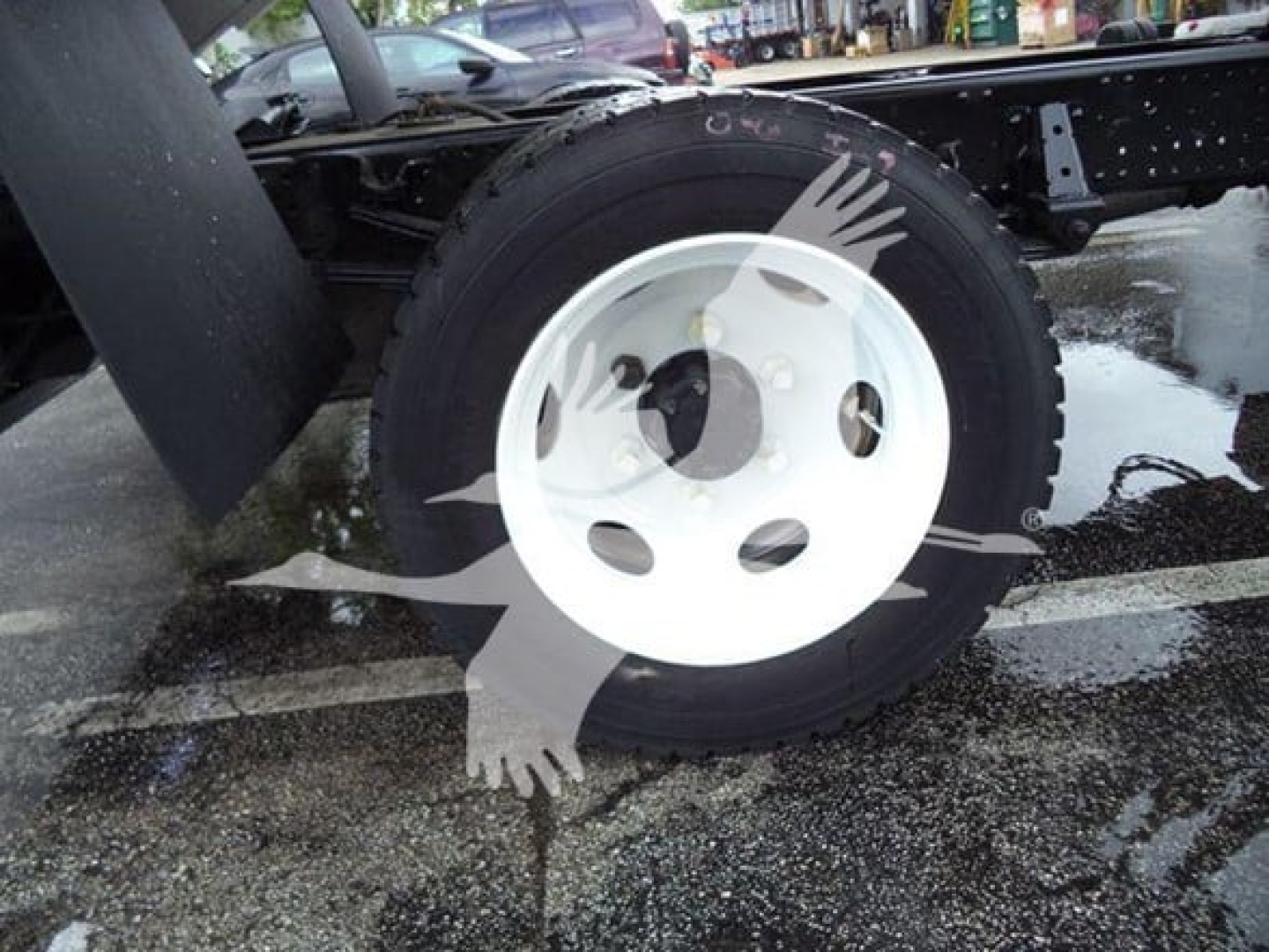 Isuzu NPR-XD wheel and tire assembly with white steel rim showing mounting hub area and partial chassis.