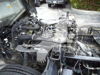 Isuzu NPR XD engine bay view showing exposed diesel engine with components and wiring.