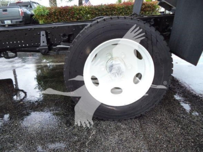 Isuzu NPR XD truck wheel and chassis section showing a white steel rim and tire on a wet pavement.