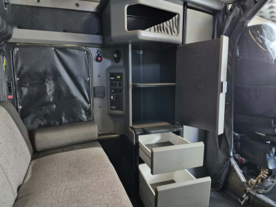 Cab interior of 2022 Kenworth W900L showing storage drawer and open cabinet in sleeper area.