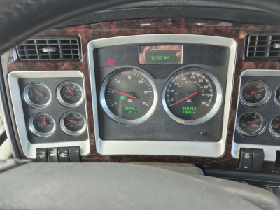 Kenworth W900L dash cluster and gauge panel with multiple analog gauges and digital clock, wood grain trim, steering wheel visible