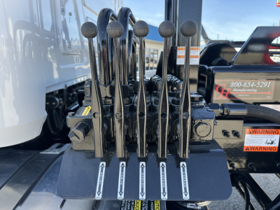 Levers and control levers on Mack GR64B rollover truck control console with labels and warning placards.