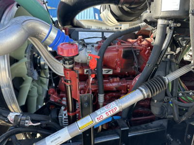 Mack GR64B engine bay showing red engine block, hoses, and orange/lred components with labels and a NO STEP decal on a cylindrical pipe.