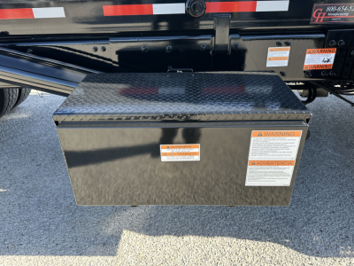 Rolloff truck chassis area with diamond-plate toolbox mounted on side, warning labels visible on toolbox.
