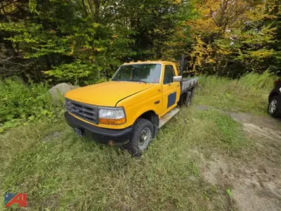 Yellow 1996 Ford F-250 flatbed truck in grassy lot, VIN 2FTHF26H1TCA52521 visible on listing