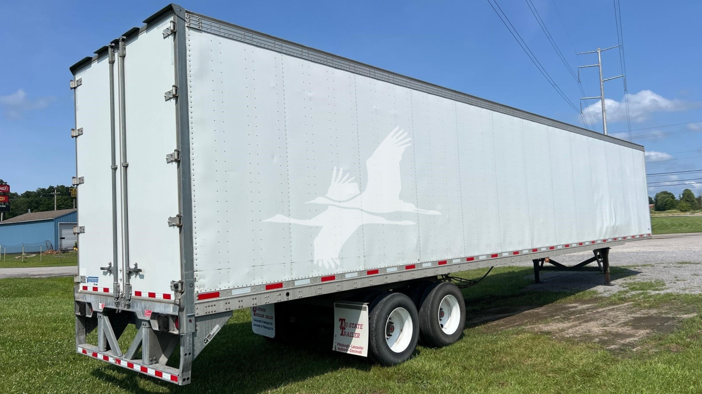 Trailer in-service showing silver cargo trailer with white seagull graphic on side, rear doors, dual rear axles, and reflective striping.