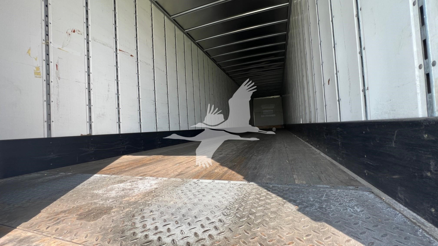 Interior of trailer trailer bay showing metal floor with diamond plate pattern and empty space toward cab with light entering from rear.