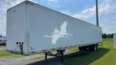 Trailer side view showing white bird graphic on light gray surface and landing gear visible.