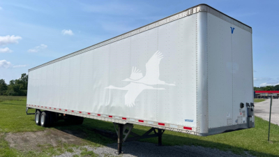Trailer side showing large graphic of a flying crane logo, with light gray/white color; rear area shows support legs and small text near bumper; no license plate visible.