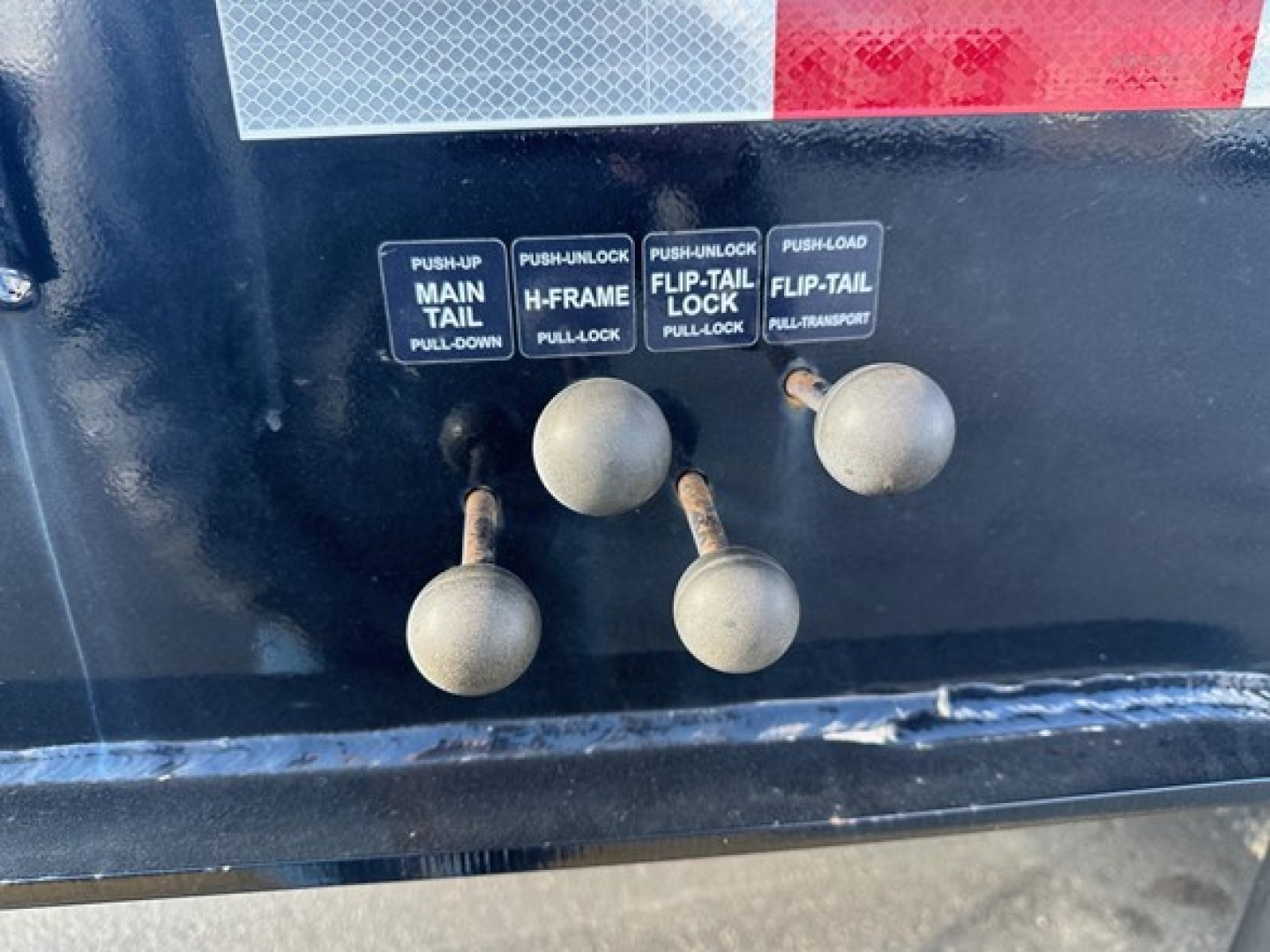 Trailer control panel with four push-pull levers labeled MAIN TAIL, H-FRAME, FLIP-TAIL, FLIP-TAIL and two push-type handles on a Trailking trailer.