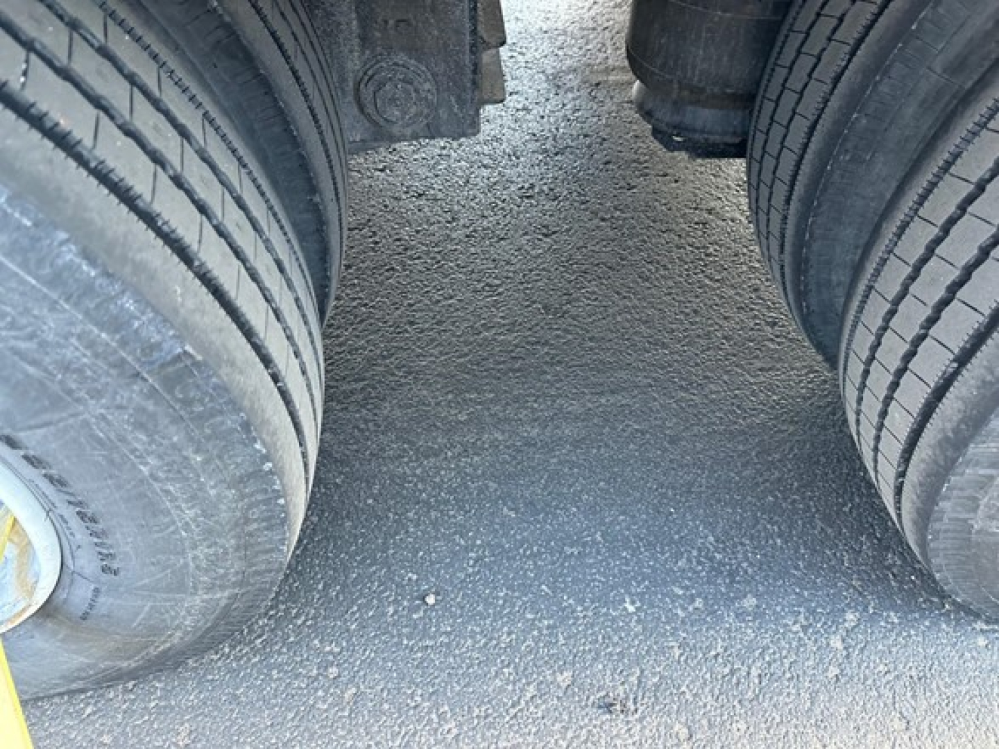 Dual rear tires of a trailer axle setup on pavement with visible tread and rims.