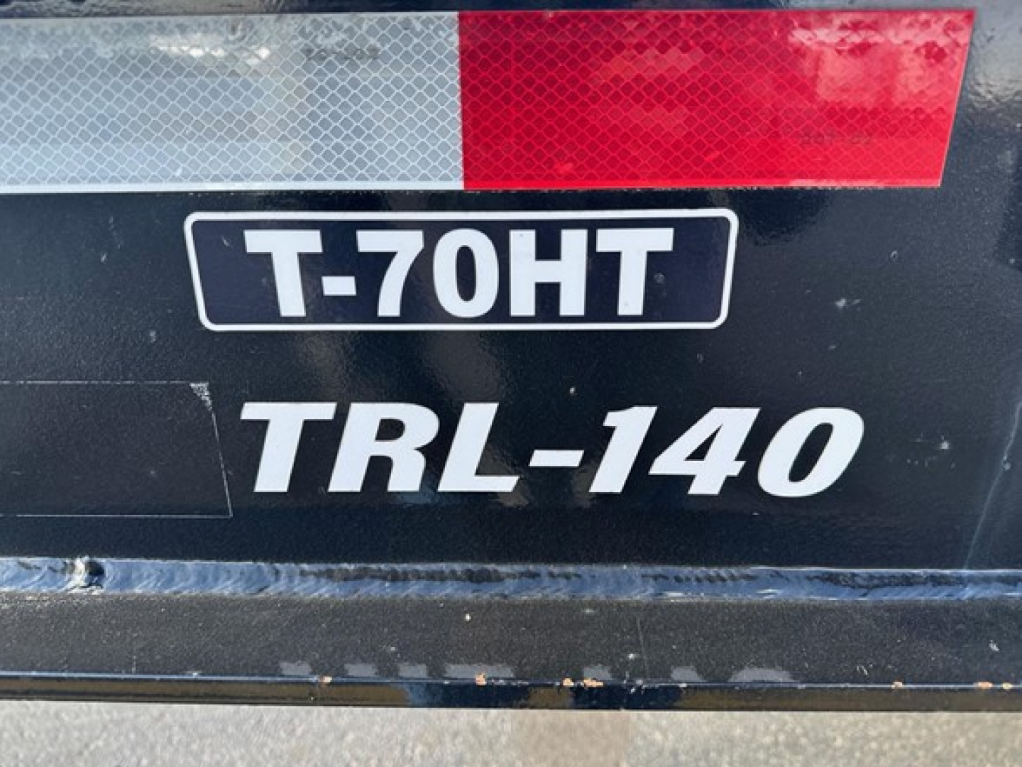 Trailer label showing T-70HT TRL-140 and red/white reflective stripe on trailer surface.