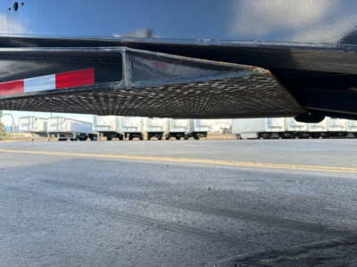 Trailer hitch step or underride grate with diamond plate pattern under trailer. Visible text not legible.
