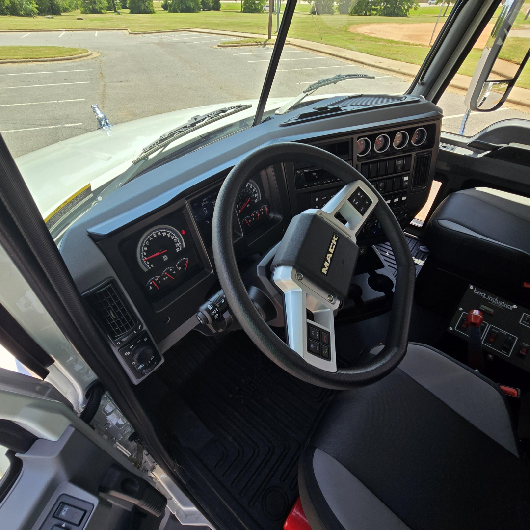 Mack GR64B cab interior showing steering wheel and dashboard gauges.