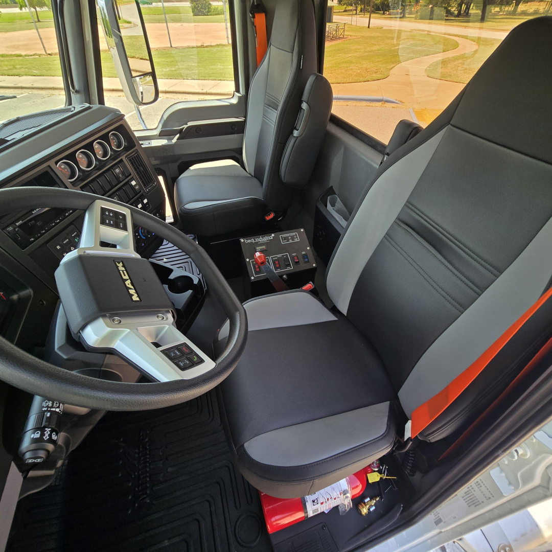 Cockpit of a 2027 Mack GR64B mixer truck showing steering wheel, dashboard gauges, and driver seat