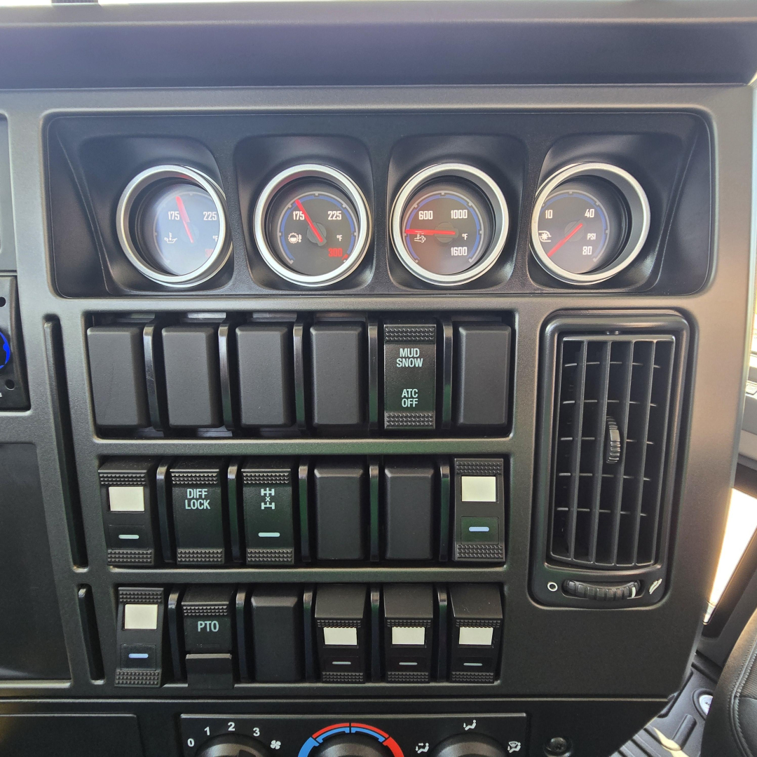 Dashboard gauges and switches of a 2027 Mack GR64B mixer truck showing multiple analog gauges and control switches.