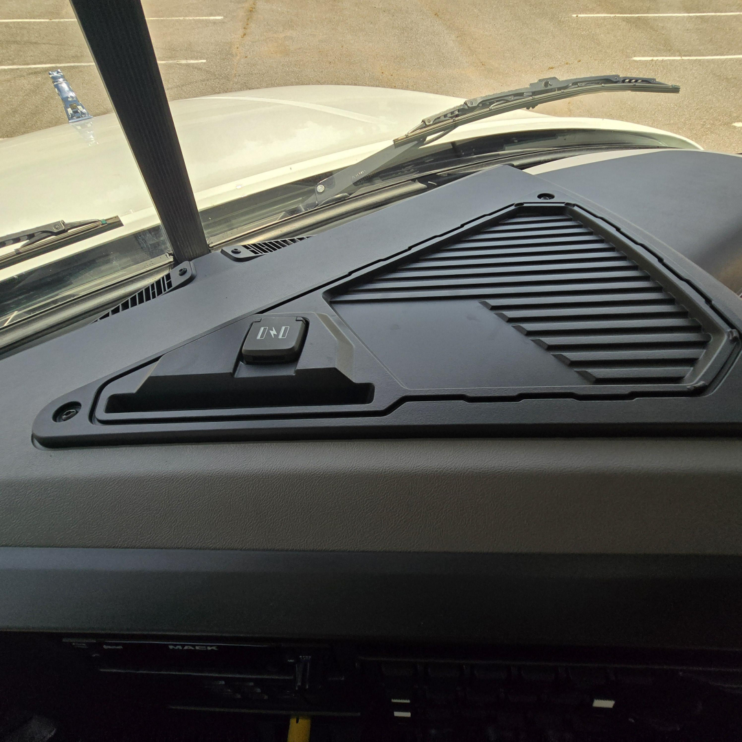 Dashboard view of a Mack GR64B mixer truck showing a molded dash panel with an integrated vent and a control switch labeled with up and down arrows.