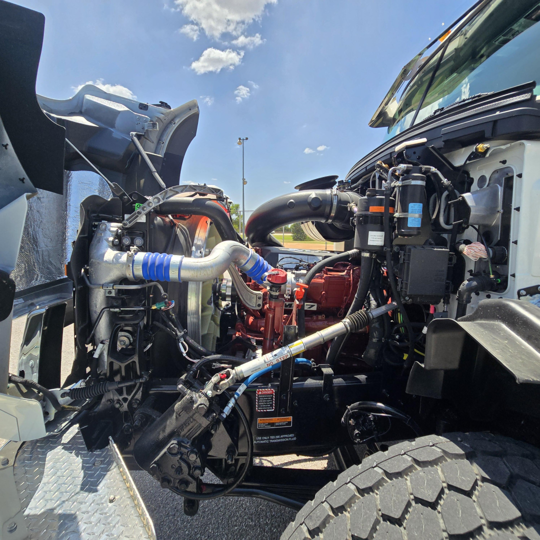 Mack GR64B mixer truck engine bay showing hoses, intercooler piping, and engine components with blue silicone hose coupling and red engine block.