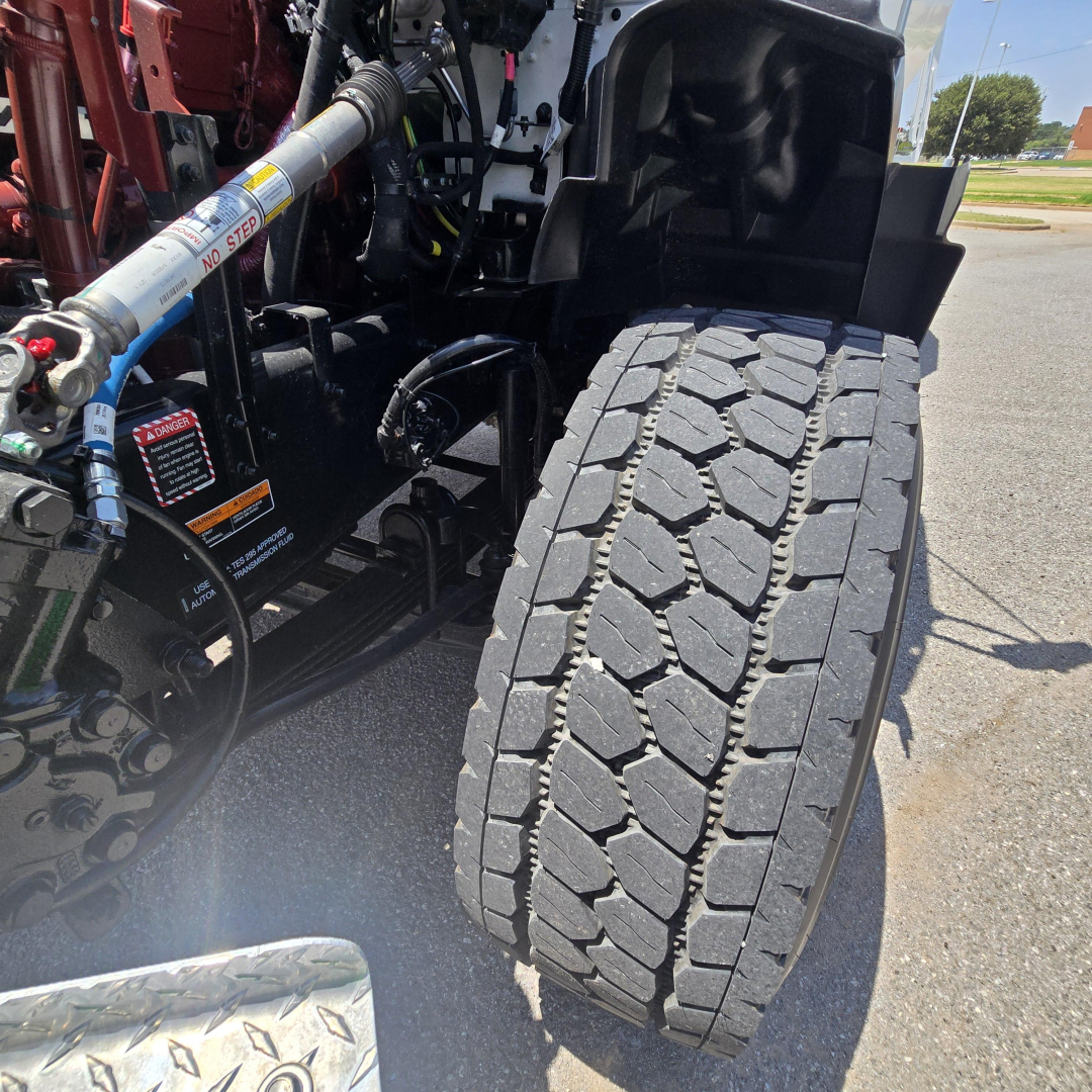 Mack GR64B wheel and front suspension showing heavy-duty truck tire tread and hydraulic lines