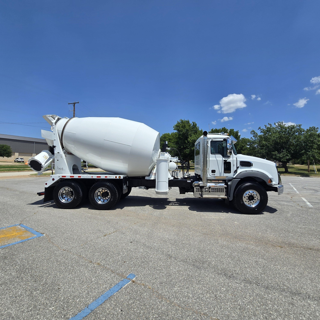 Mixer truck with white cement mixer body and cab, 6-wheel configuration, side view, in a parking lot.