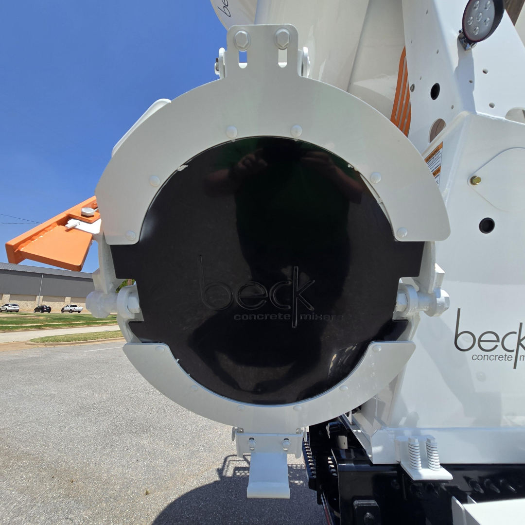 Mixer truck rear hitch area showing circular black cover with beige frame and hydraulic components; Beck concrete mixers branding faint on cover.
