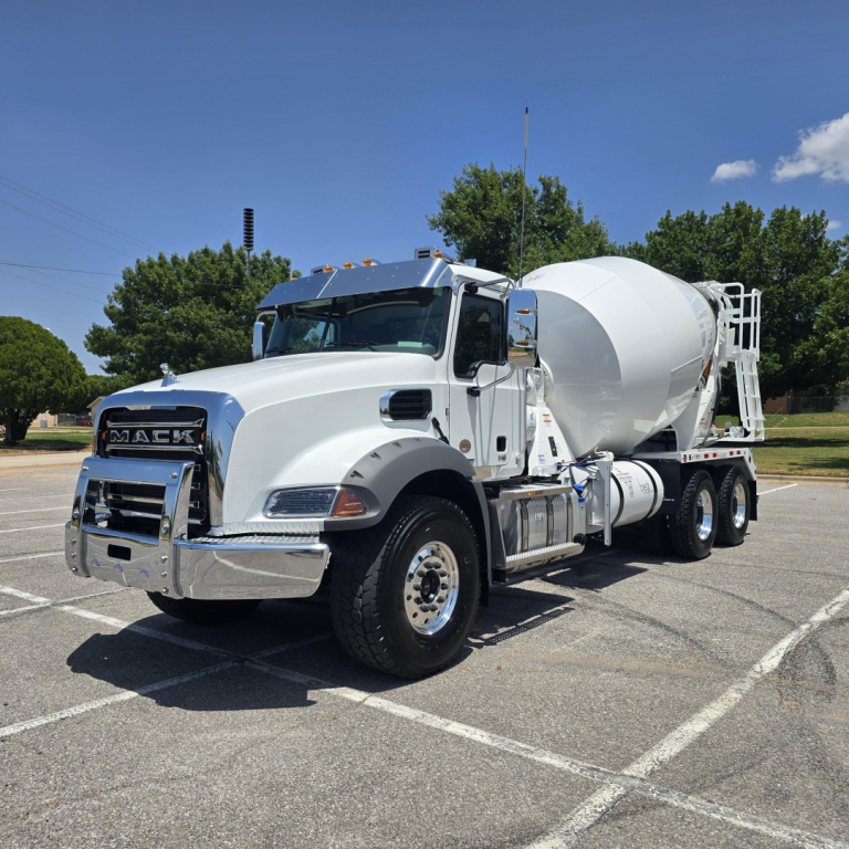 Mack GR64B mixer truck in a parking lot, white cab and cement mixer on long chassis with chrome accents.