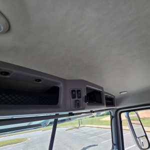 Cab interior top storage and controls of a Mack GR64B mixer truck cabin, with overhead compartments and small switches visible