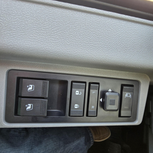 Dashboard panel with window controls, mirror adjust, and switches in Mack GR64B truck cab. Visible text on switches including window icons and mirror/lock symbols.