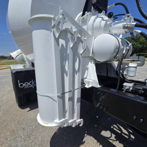 Mixer truck hitch and hydraulic components on Mack GR64B chassis showing large white mounting brackets and hydraulic lines.