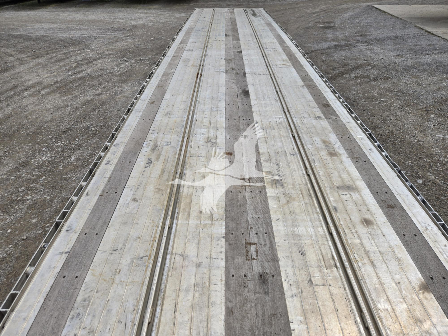 Aluminum drop deck trailer bed showing multiple longitudinal grooves and wear marks.