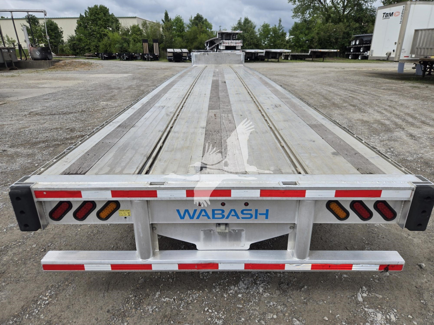 Trailer rear showing WABASH aluminum drop deck trailer with reflective strips and taillights.