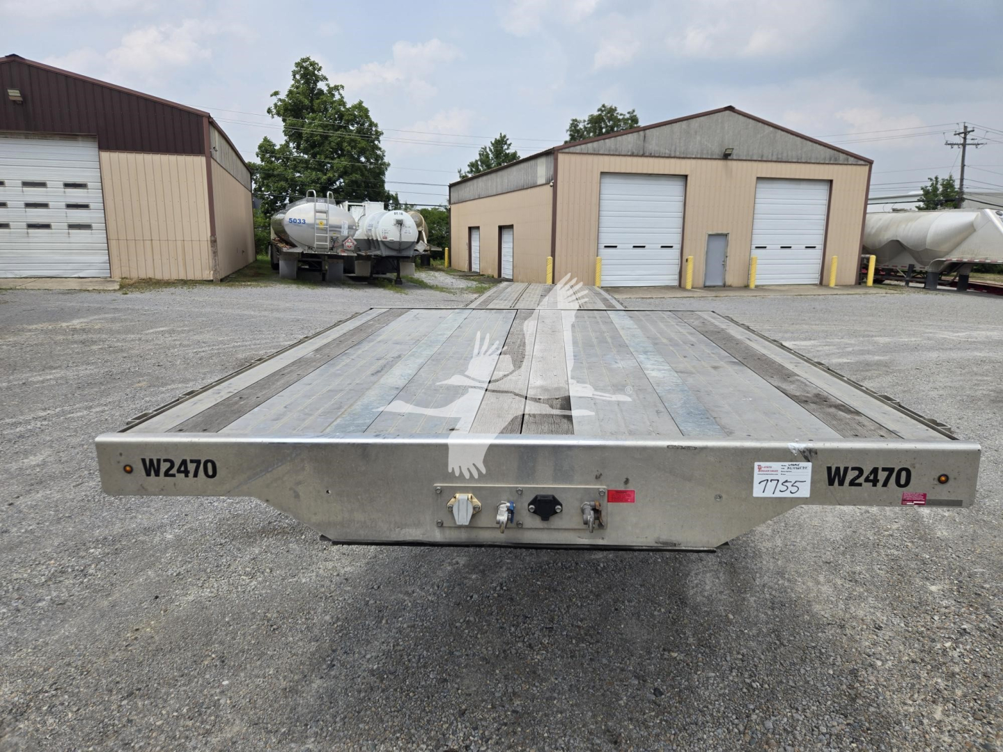 Wabash drop-deck trailer rear view showing metal deck, side brackets, and hitch area with stock number plate; W2470 markings on both ends.