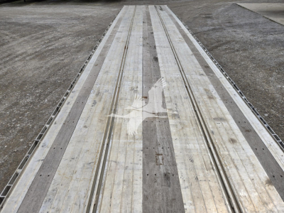 Aluminum drop deck trailer bed showing multiple longitudinal grooves and wear marks.