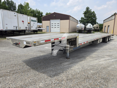 Aluminum drop deck trailer in a gravel lot, viewed from front-left, showing landing gear and deck with reflective tape; 