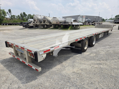 Long Wabash drop deck trailer showing aluminum flatbed with triple-axle rear and rear bumper, reflective tape, and 'WABASH' branding at tail.
