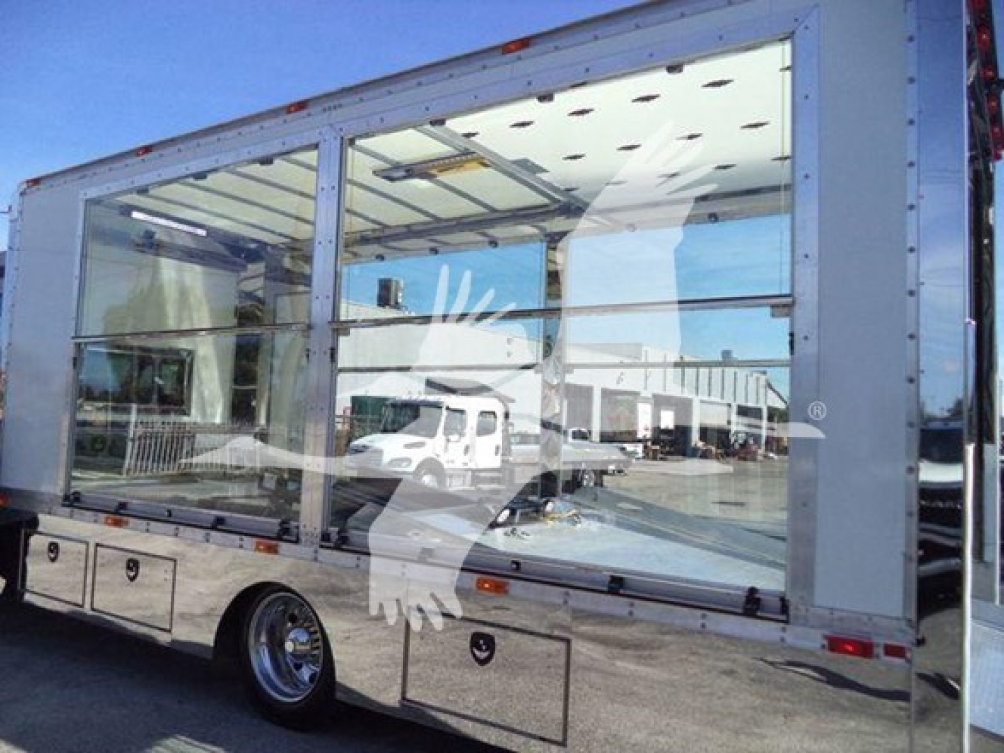 Kenworth T280 rollback truck side view showing large glass cab and metallic body panels with reflections.
