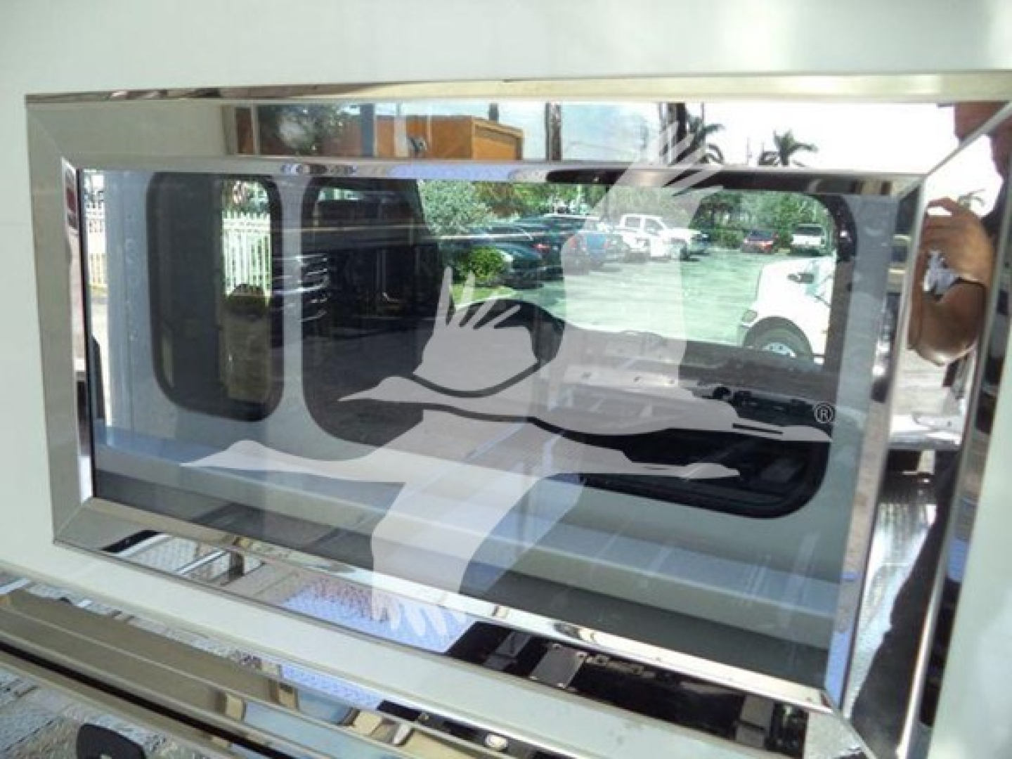 Vehicle equipment image showing a chrome-framed window or display with reflective surface and a duck silhouette design.