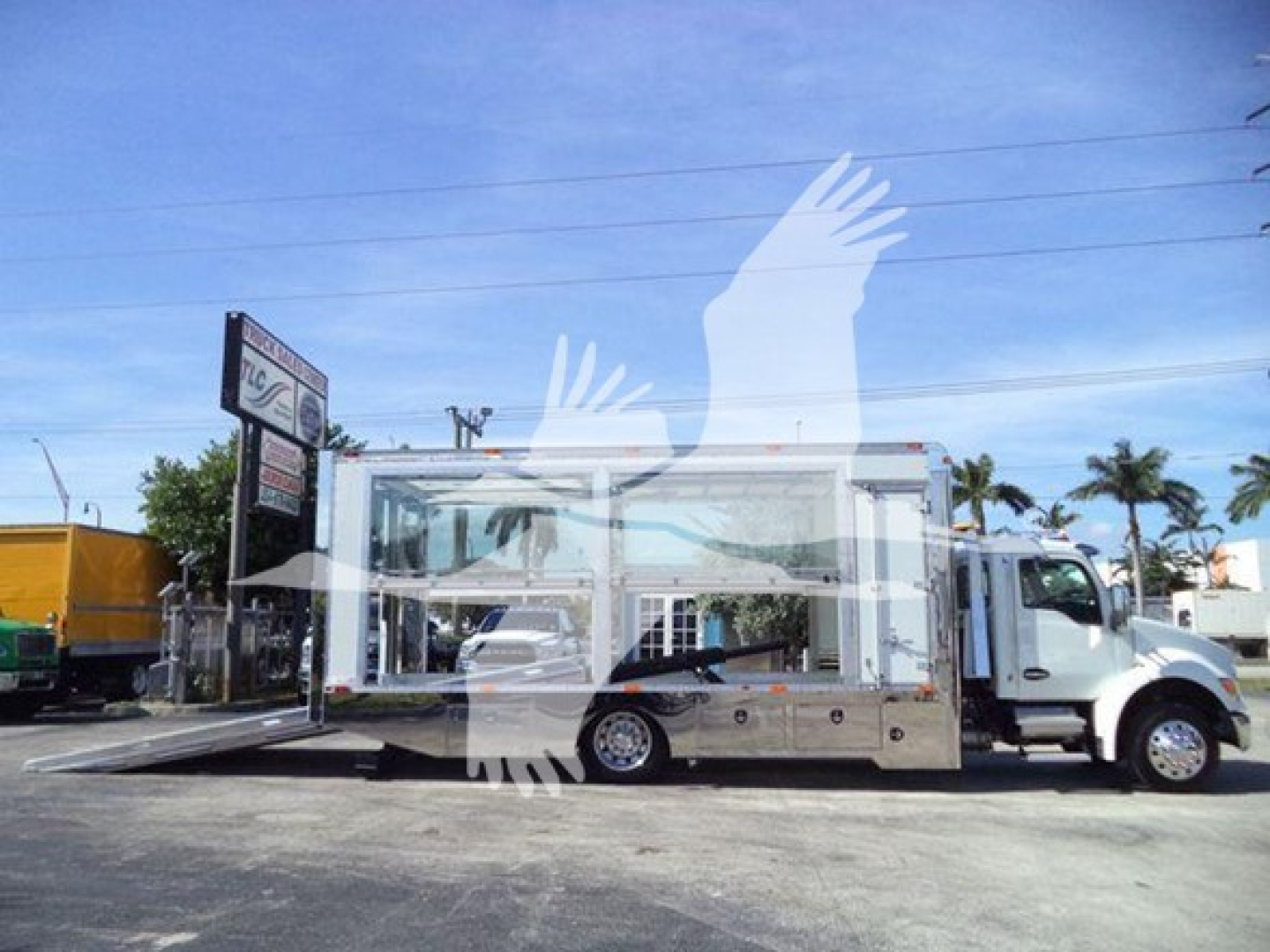 Kenworth T280 rollback truck with hydraulic ramp and chrome toolboxes, side view showing cab and flatbed area.