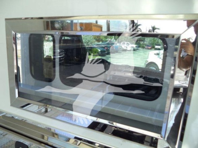 Vehicle equipment image showing a chrome-framed window or display with reflective surface and a duck silhouette design.