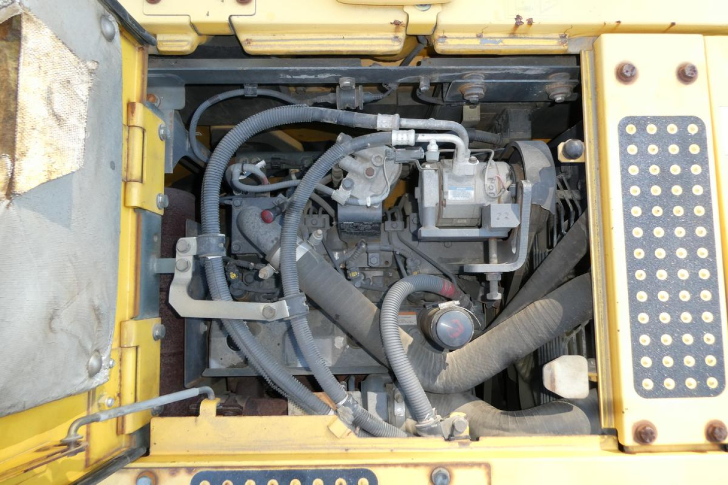 Komatsu PC128US-8 engine bay view showing hydraulic hoses and components.