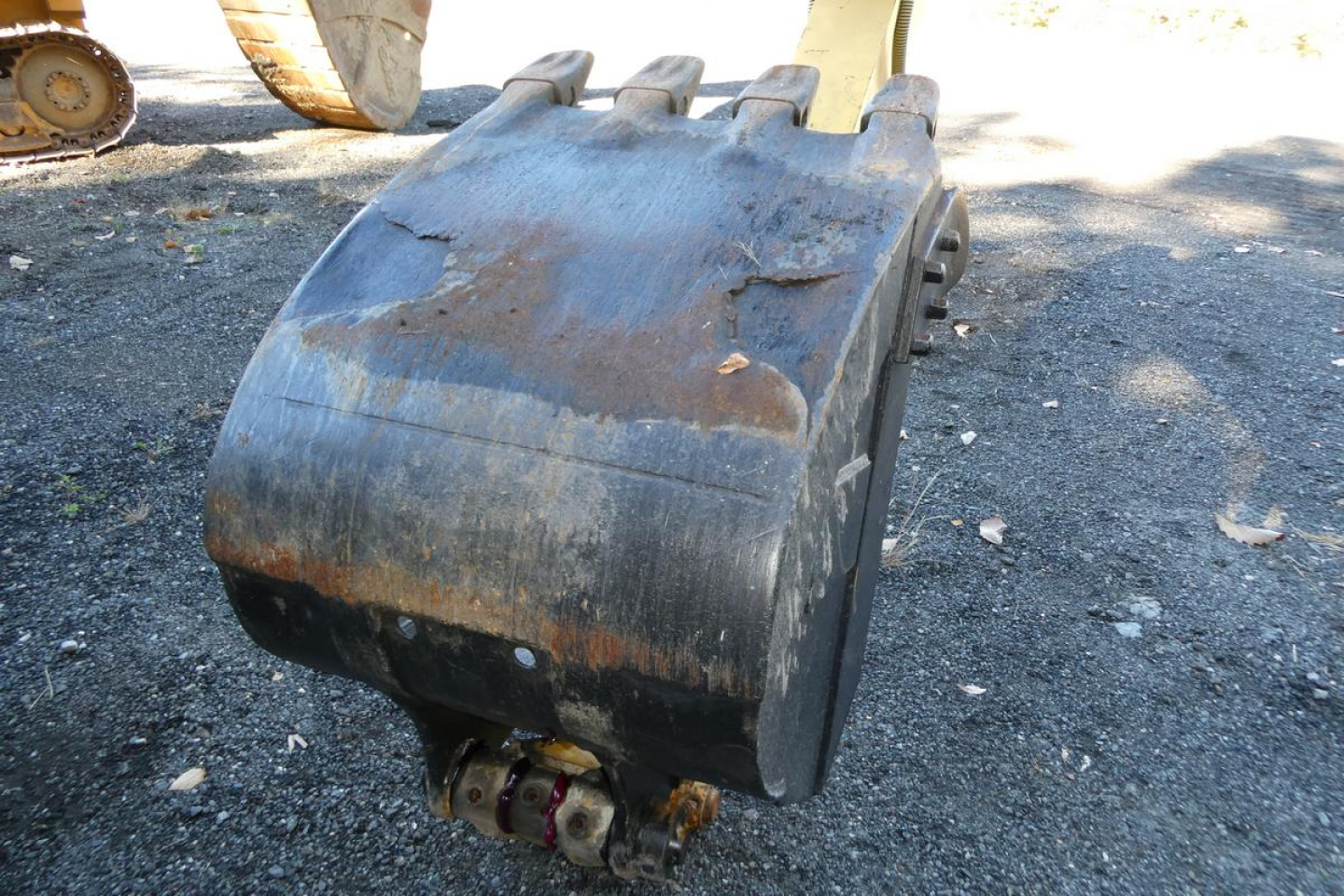 Komatsu PC128US-8 excavator bucket attachment with wear and rust-free edges, view of the bucket sitting on gravel.