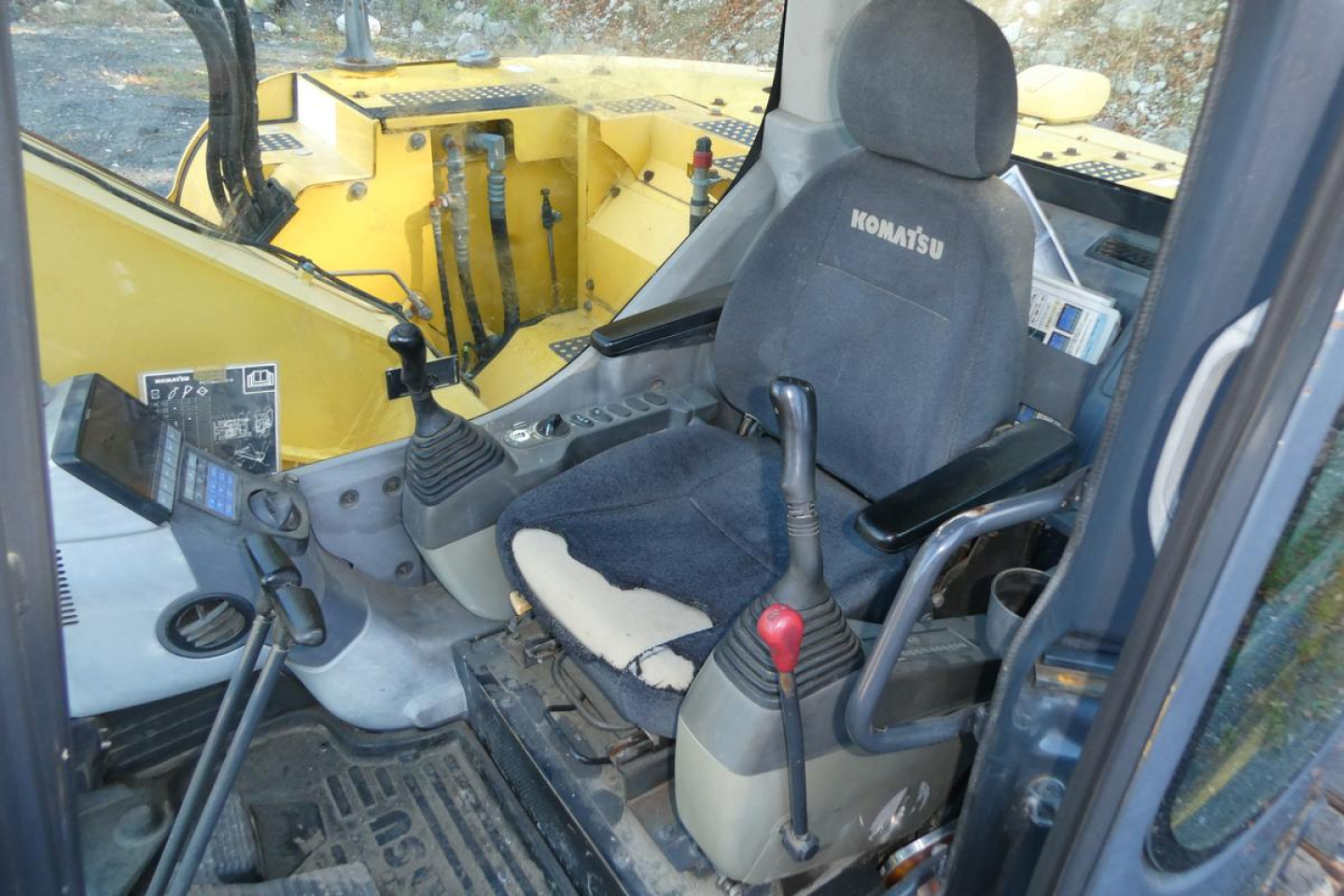 Komatsu PC128US-8 excavator cab interior showing operator seat and controls.