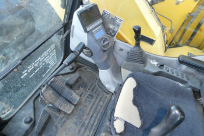Komatsu PC128US-8 cab interior showing joystick controls and dashboard with digital display.