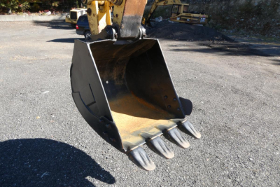 Excavator bucket attachment on a Komatsu PC128US-8 showing medium-duty steel bucket with teeth and hydraulic coupler.